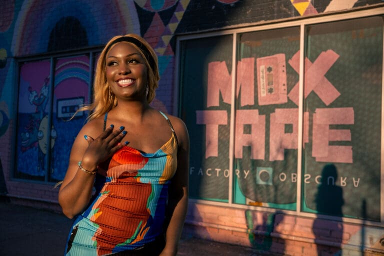 Featured Music Career May 2026 - Ellesse. Woman standing next to a sign that says Mix Tape.
