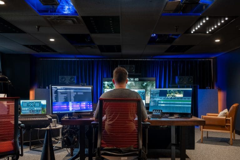 a man who works at audio planet sitting in a dark room working on sound design at a computer